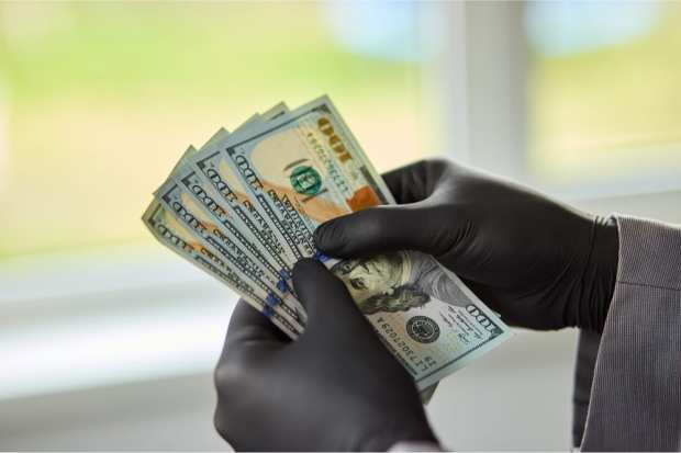 gloved hands holding cash