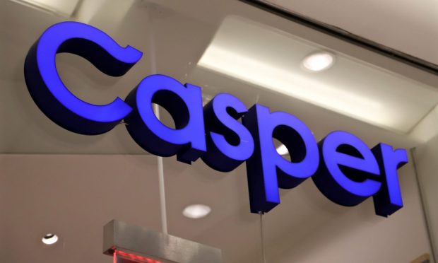 A blue Casper logo sign in a close-up view, mounted on a glass window