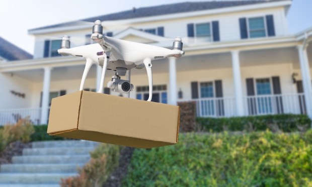 drone delivering package in front of house