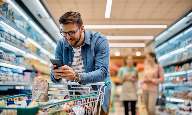 man grocery shopping in store with phone