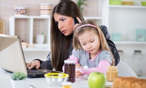 woman on phone with laptop and child