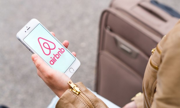 phone with Airbnb app, suitcase