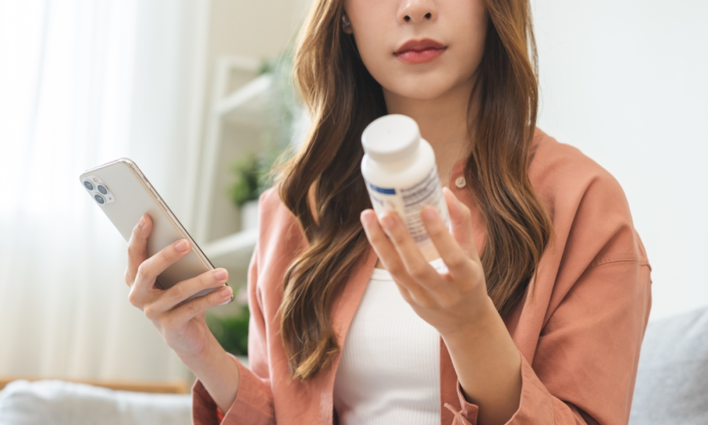 woman with pill bottle and phone