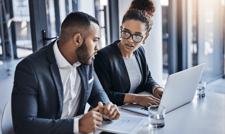2 businesspeople working on contract at laptop