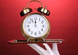 white-gloved hand with alarm clock on tray
