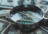 magnifying glass on top of cash