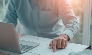 person with desk calendar and laptop