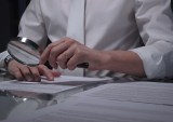 person viewing contract with magnifying glass