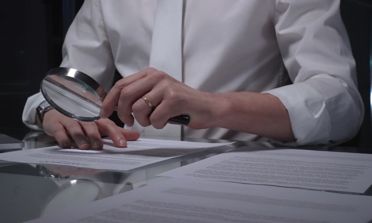 person viewing contract with magnifying glass