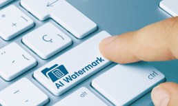 AI Watermark Written on Blue Key of Metallic Keyboard. Finger pressing key.
